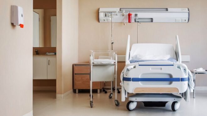 A hospital bed with a newborn bed beside it