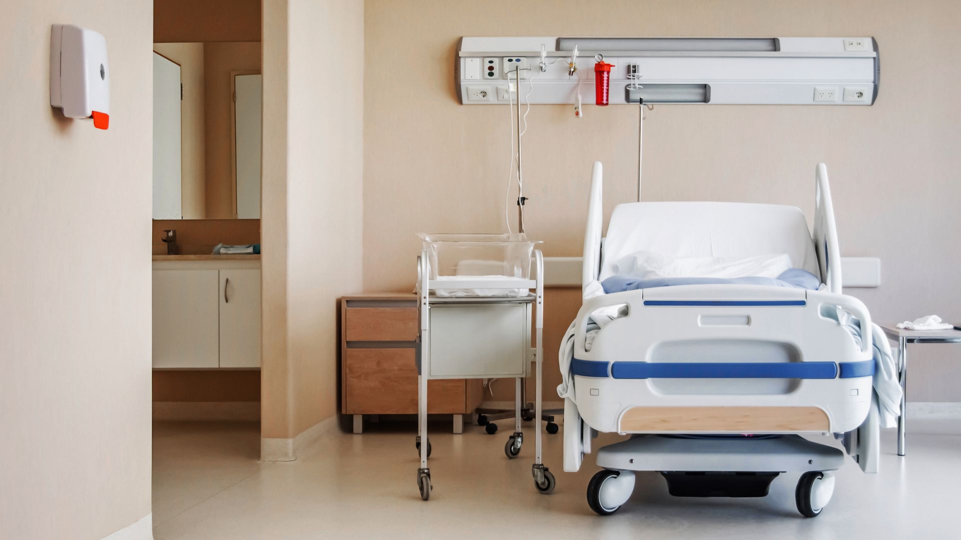A hospital bed with a newborn bed beside it
