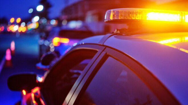 A police car stopped at night with its emergency lights on