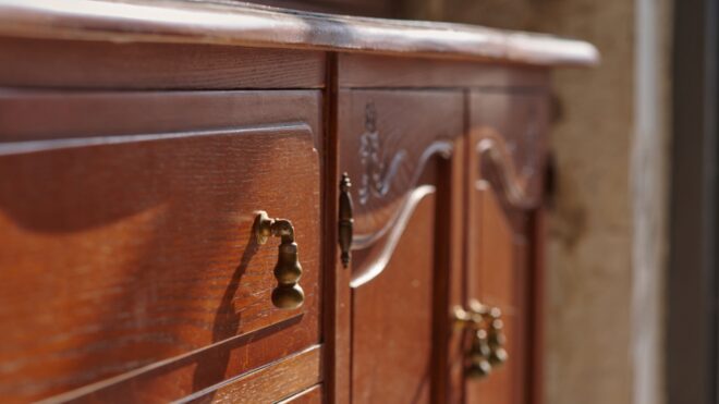 A vintage brown wood dresser showing an upclose look at the drawers and doors