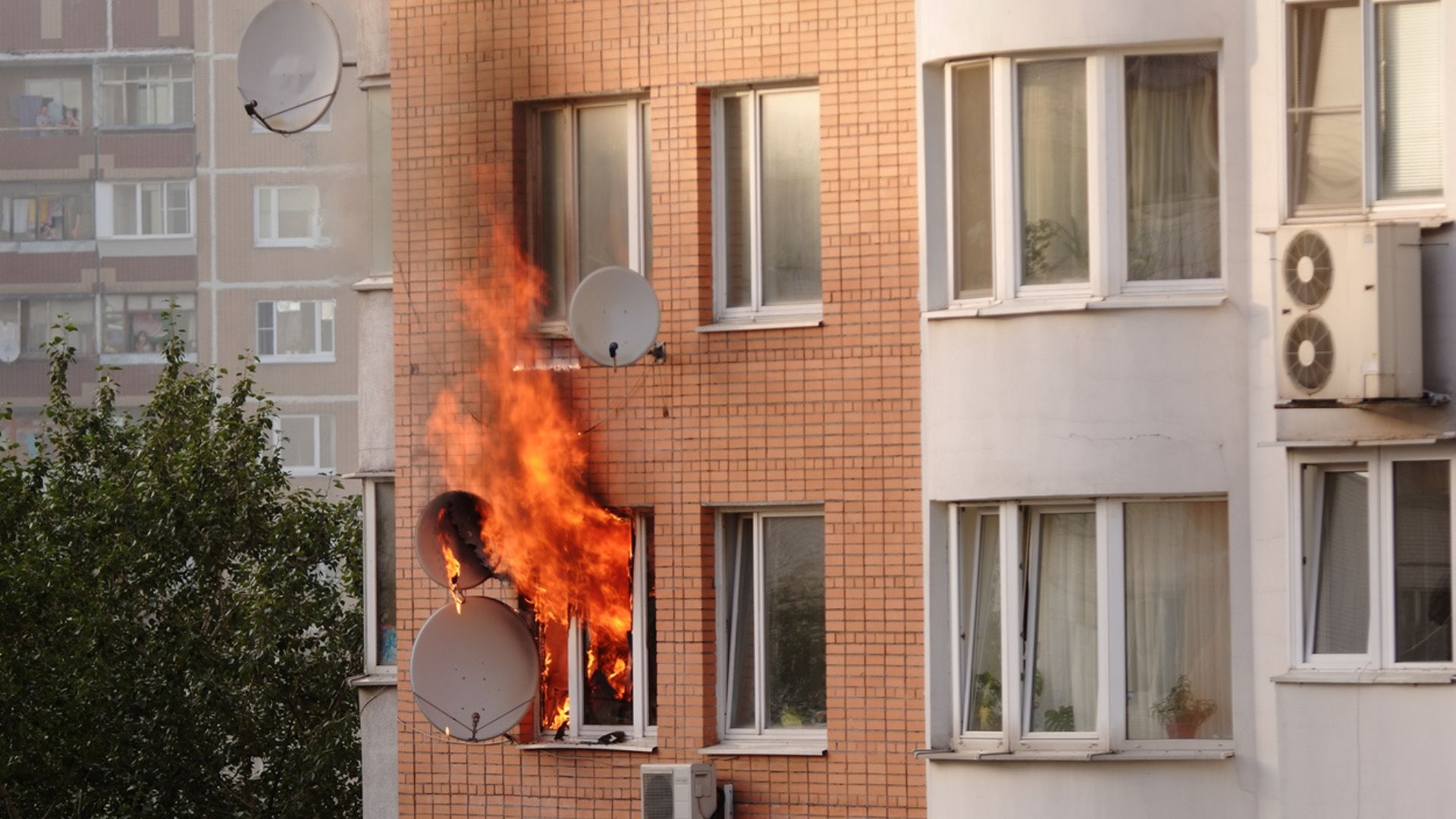 An apartment building with multiple satellite dishes on fire