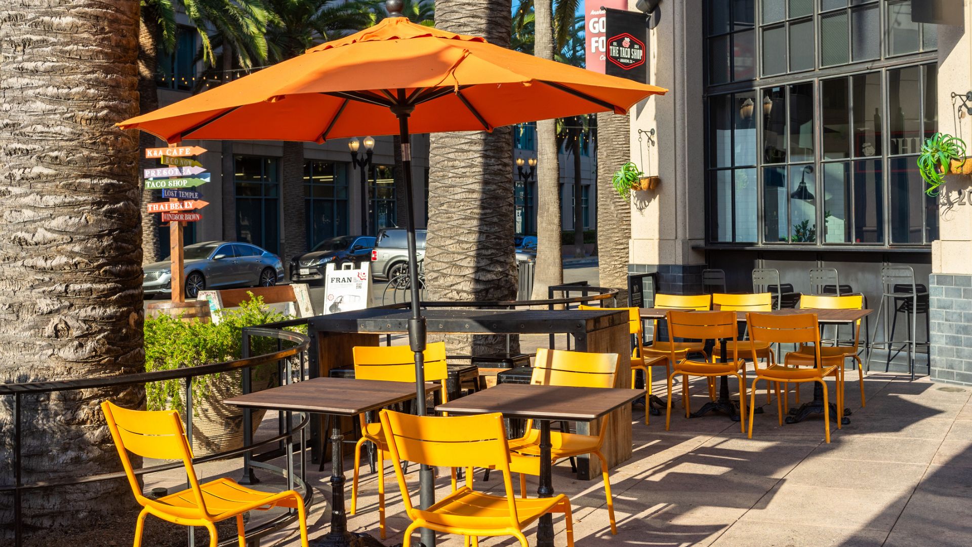 An outdoor food court patio outside a restaurant with tables and umbrellas
