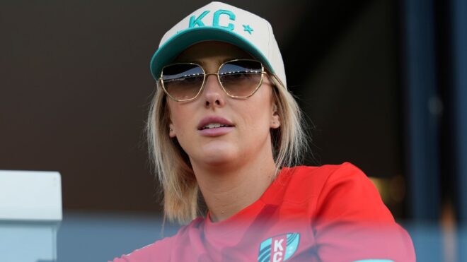 Brittany Mahomes in a hat and sunglasses looks on during the NWSL match