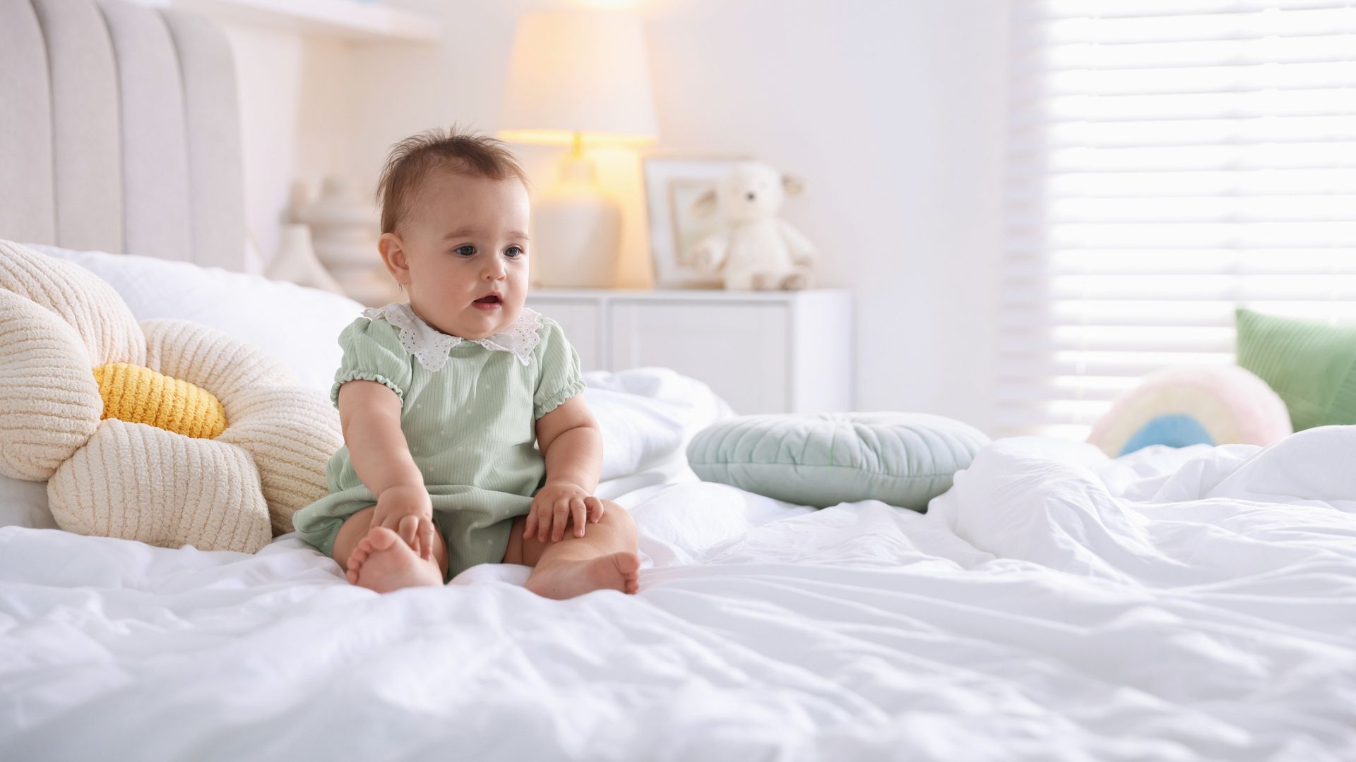 A baby sitting alone on a modern-style bed
