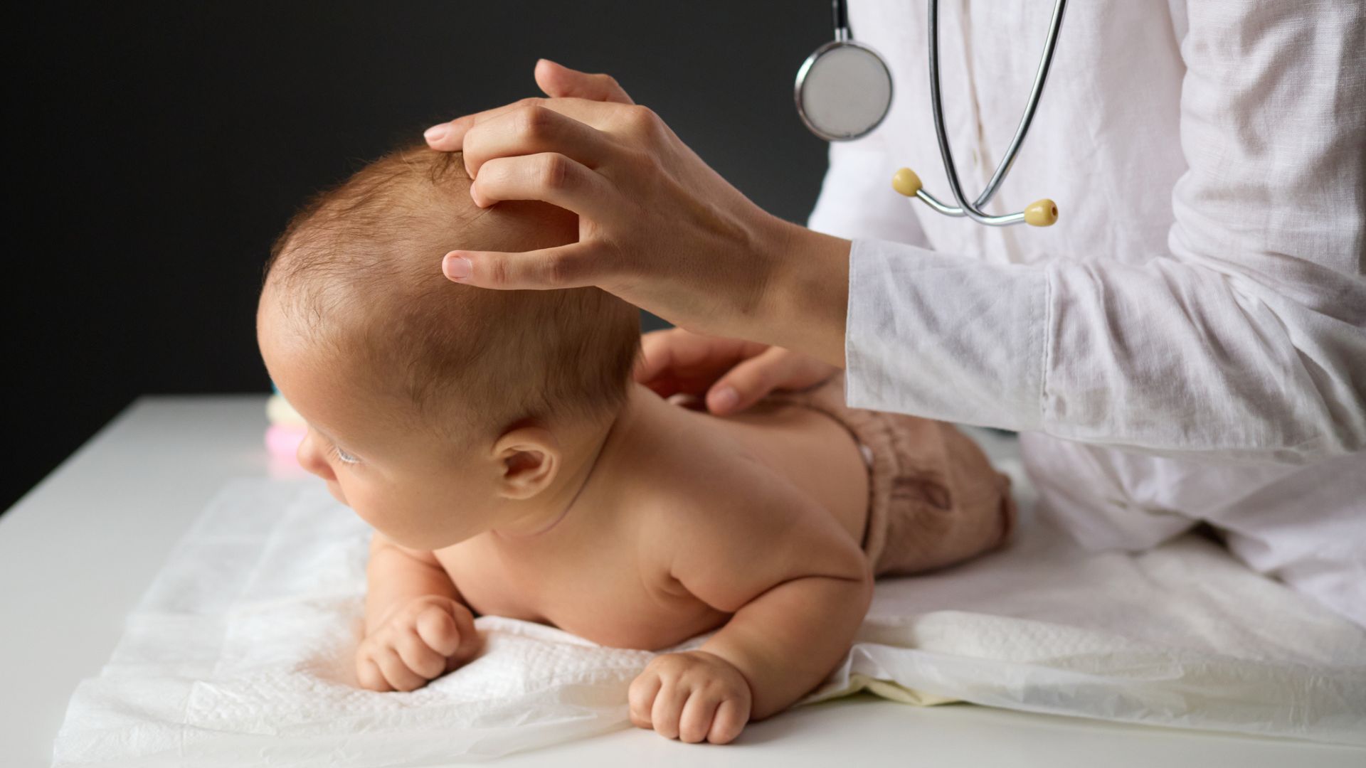 A doctor examining a baby's head on an exam table
