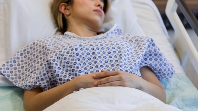A female patient in a hospital gown laying in bed