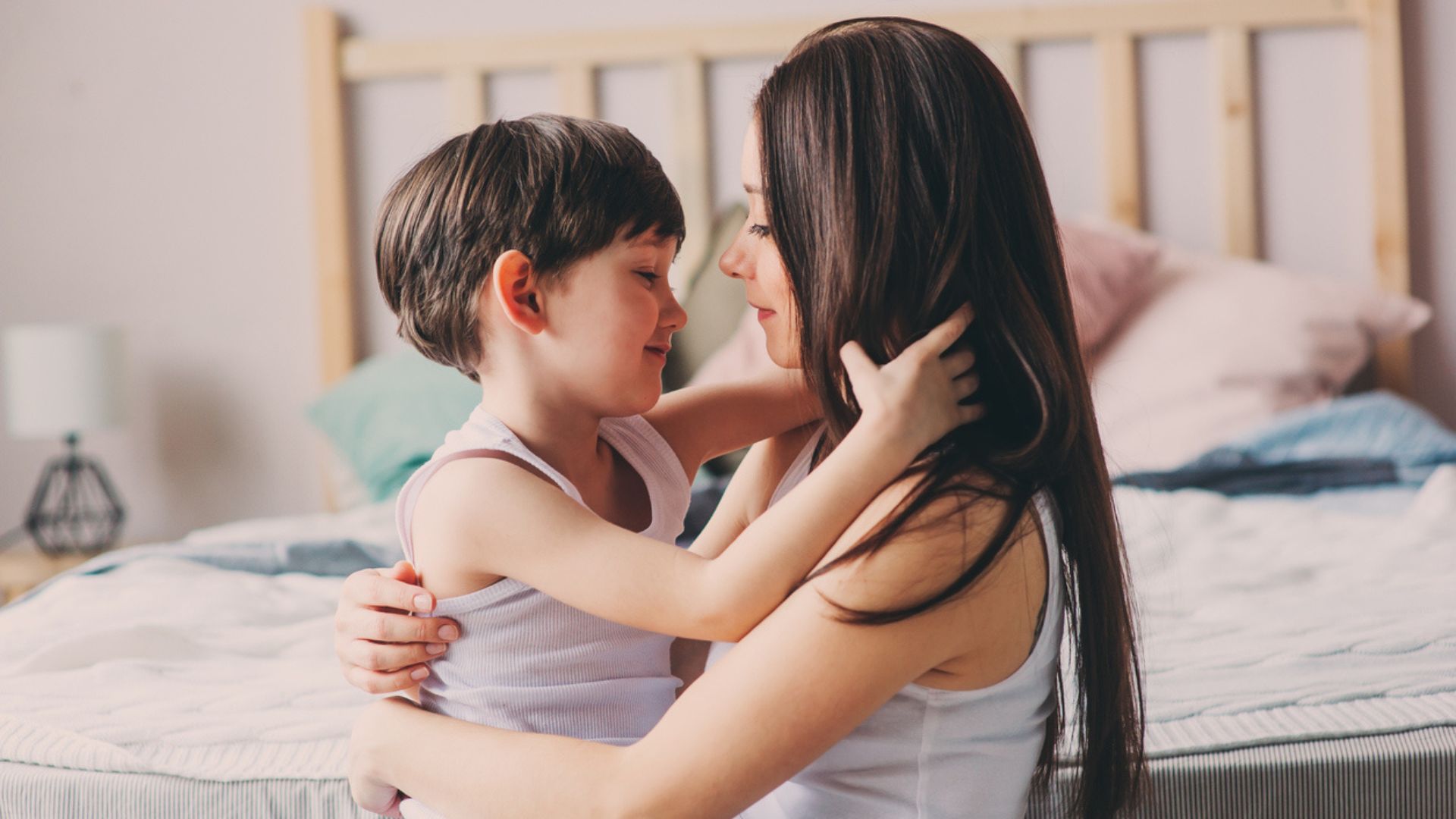 A mom hugs her toddler boy in the bedroom area in the morning