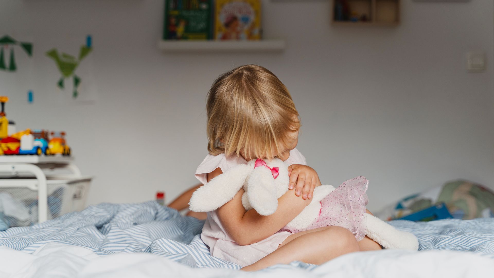 A young girl hugging a stuffed rabbit in bed