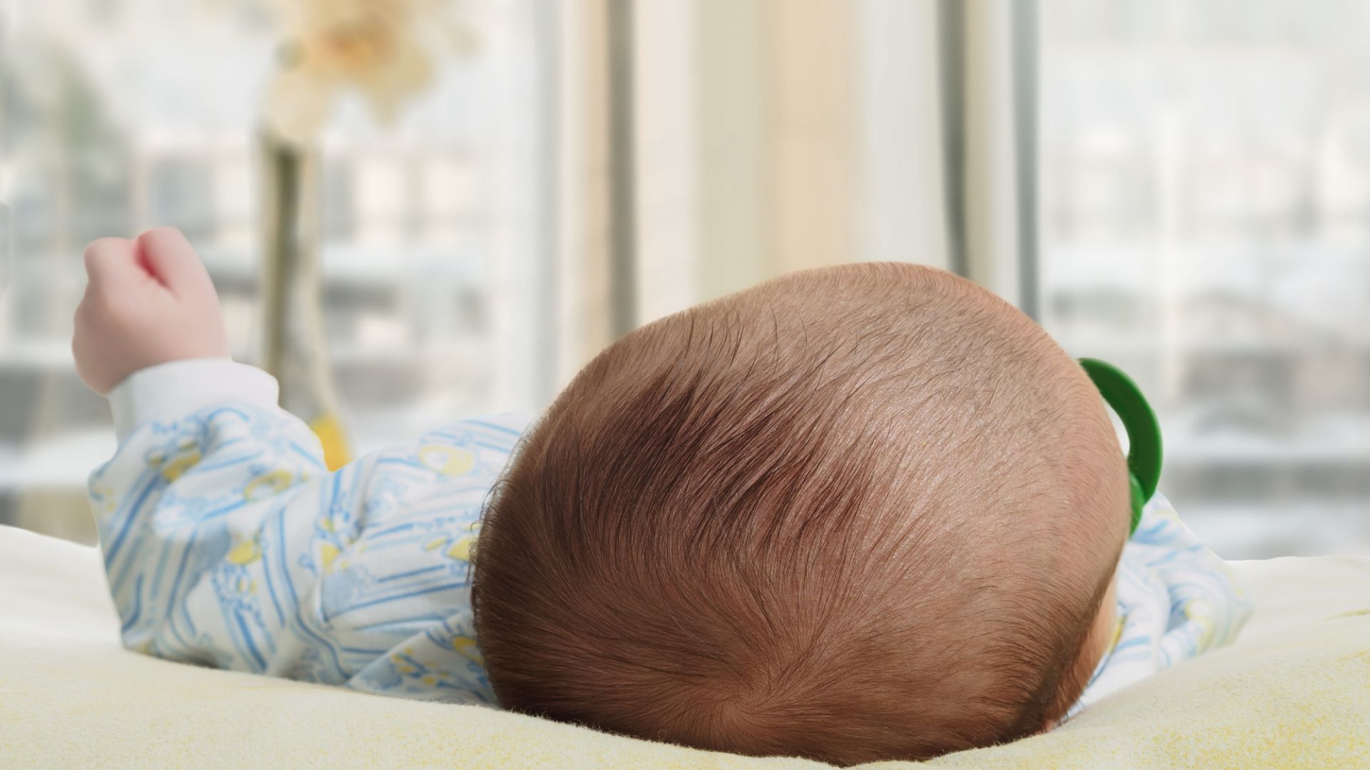 An upclose look at the back of a baby's head as they lay down in their sleeper