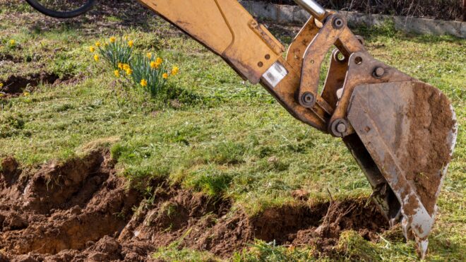 A yellow excavator digging up land