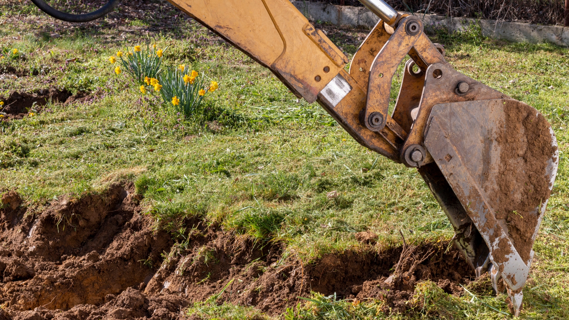 A yellow excavator digging up land