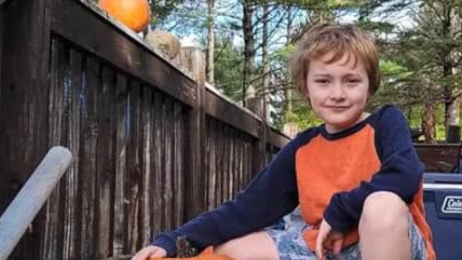 Braxton smith sitting on a porch in an orange shirt
