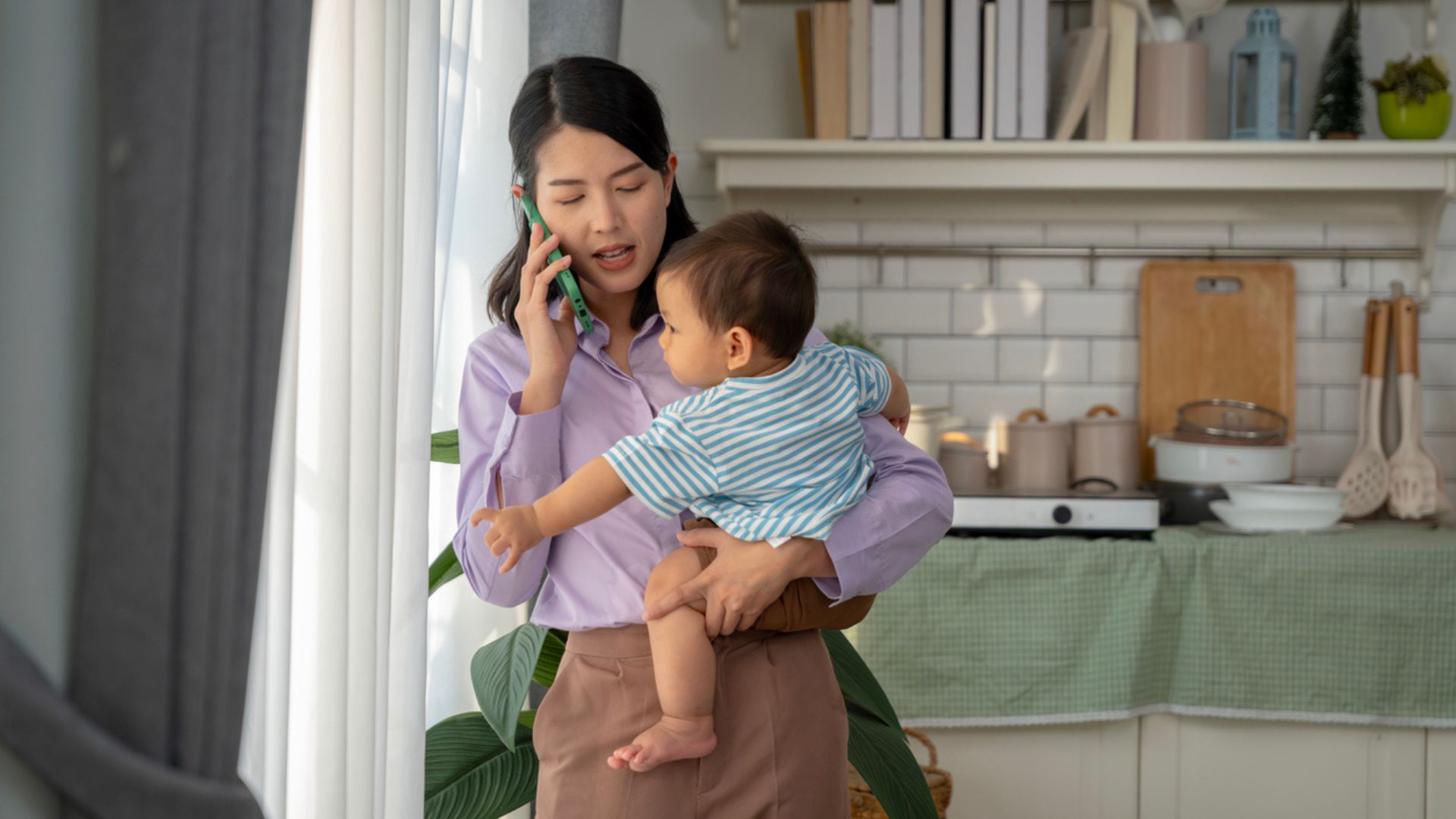 Mom with baby in her arms at home talking on the phone