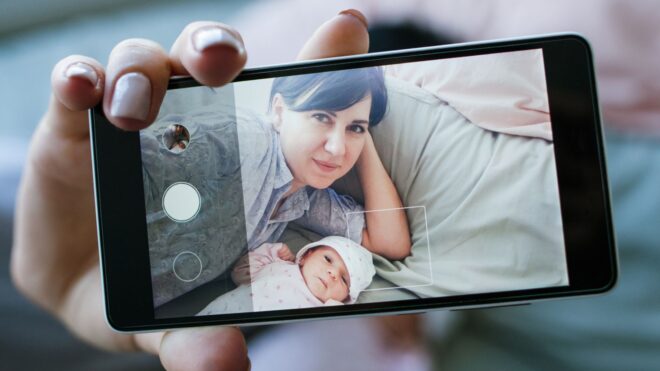 Woman posing with her Smartphone to take a photo with a baby