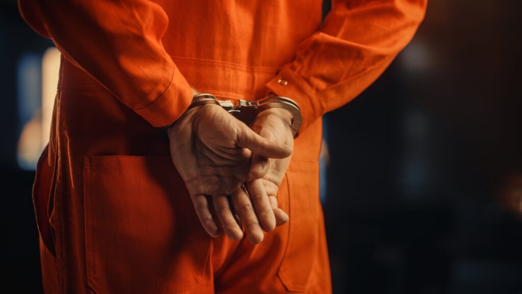 A man in handcuffs wearing an orange jumpsuit