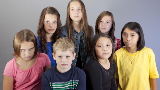 Group of serious diverse 10-year old kids on grey background