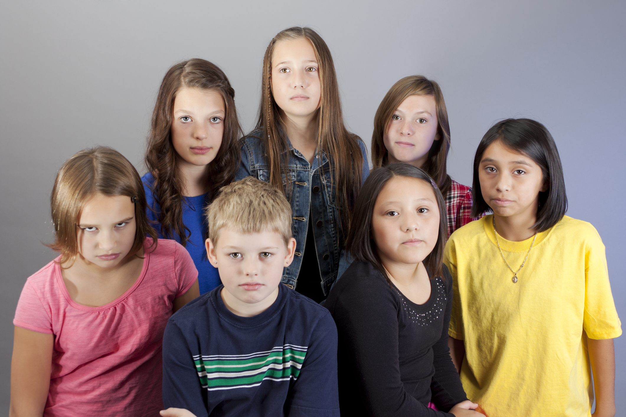 Group of serious diverse 10-year old kids on grey background