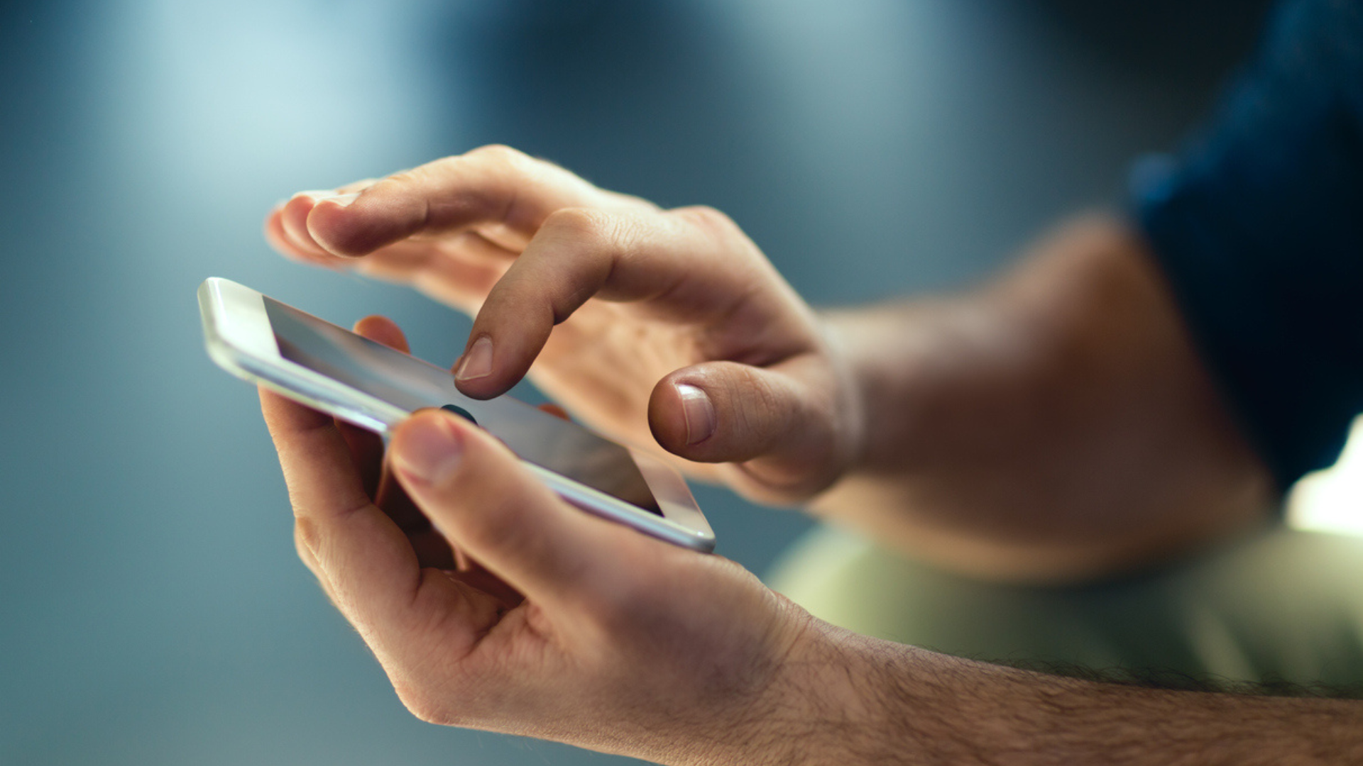 man's hands using smartphone
