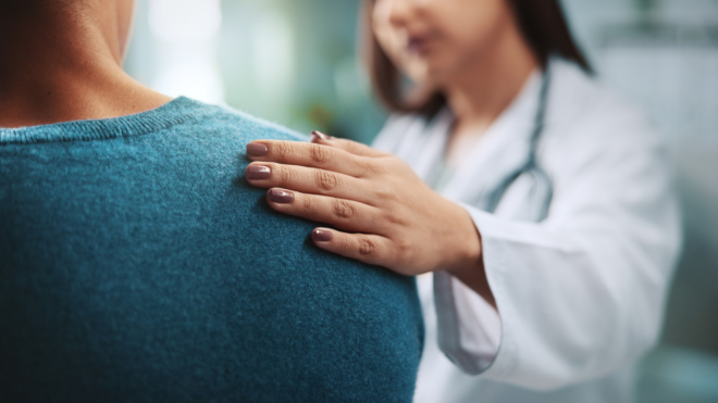 woman being comforted by a doctor hand on shoulder