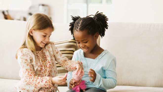Two little girls playing with a doll