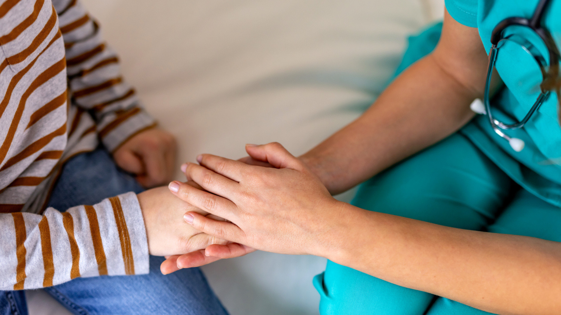 female doctor holding the hand of a young boy