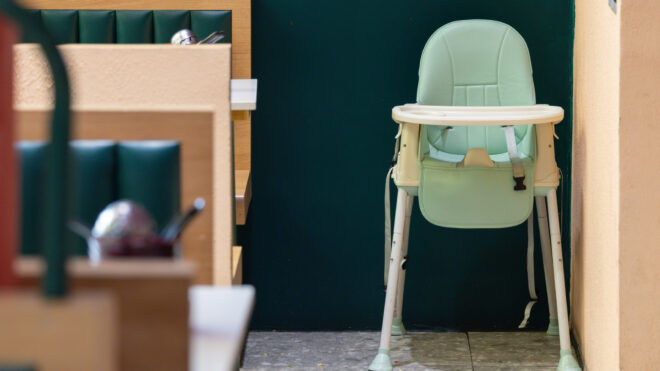 A green high chair is sitting in a restaurant