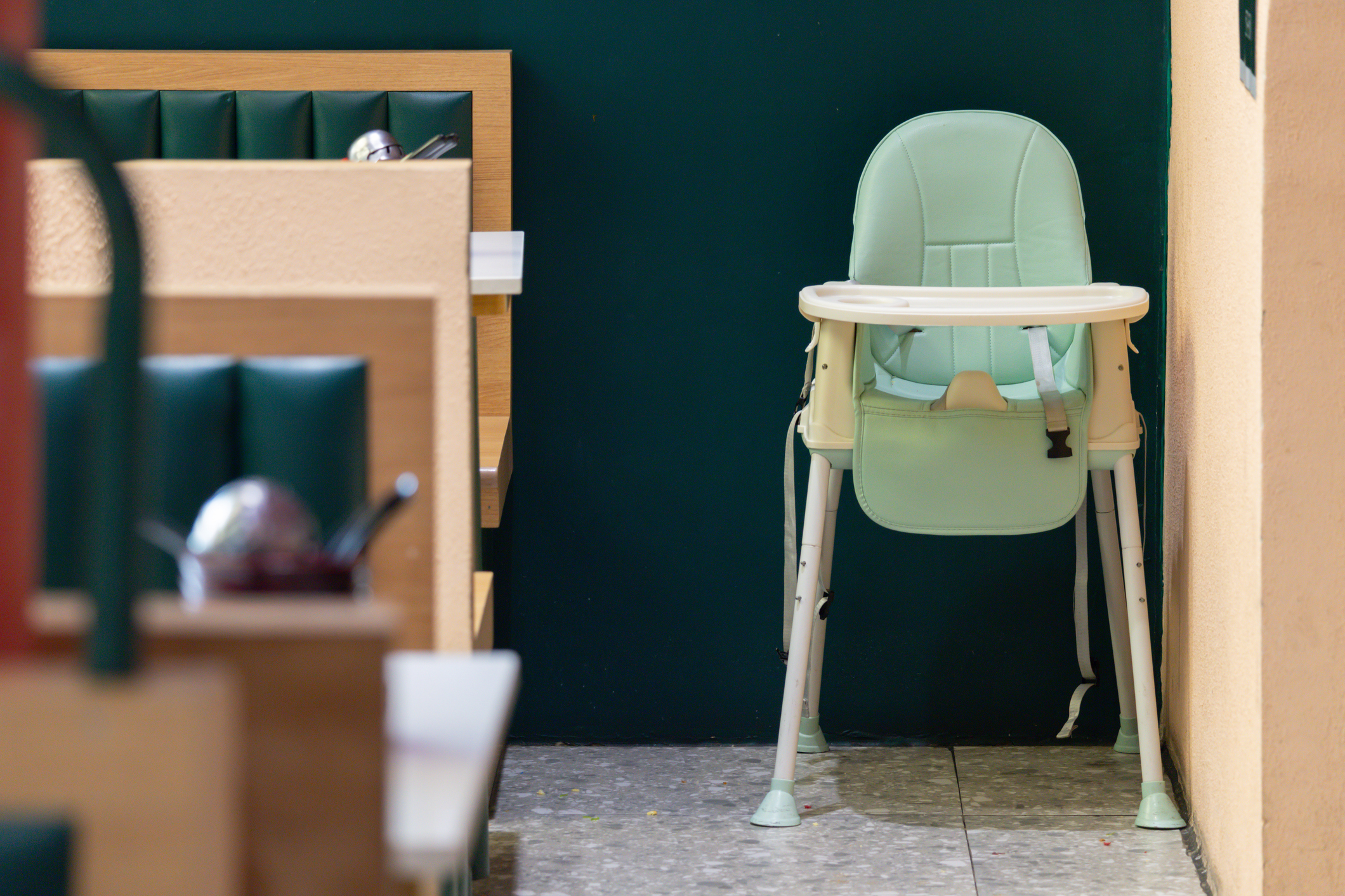 A green high chair is sitting in a restaurant