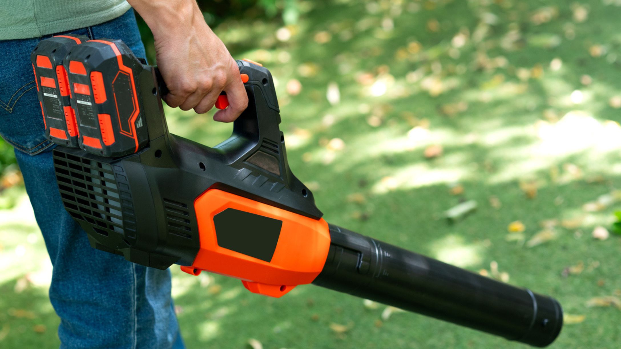 A man holding a cordless leaf blower outdoors