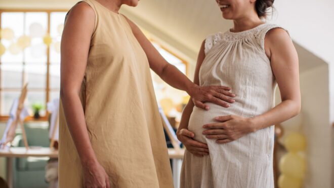 A woman placing her hand on a pregnant woman's stomach